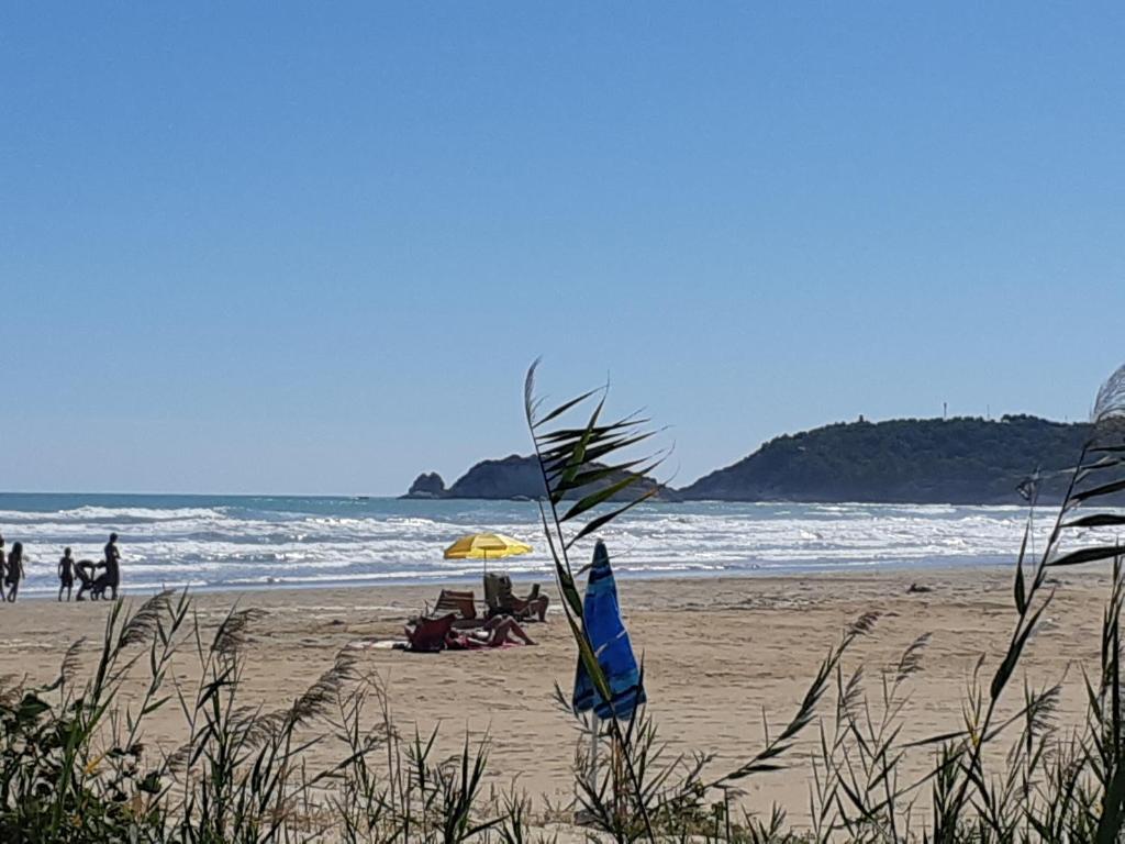 维耶斯泰La Dimora in riva al mare的沙滩上有人坐在沙滩上,还有一把遮阳伞