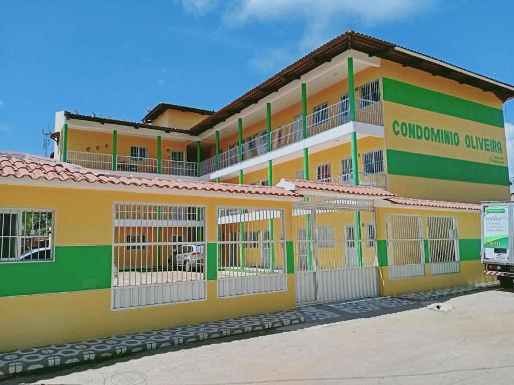 马拉戈日Condominio Oliveira的一座黄色和绿色的大建筑,设有围栏