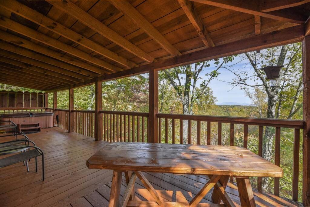赛维尔维尔View! Cozy, Private, Fireplace, Hot Tub Log Cabin, Honeymoon!的木制门廊,甲板上配有木桌
