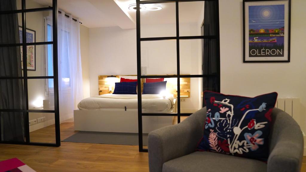 拉罗谢尔Appartements Les Rochelais的一间卧室,卧室内配有一张床和一把椅子