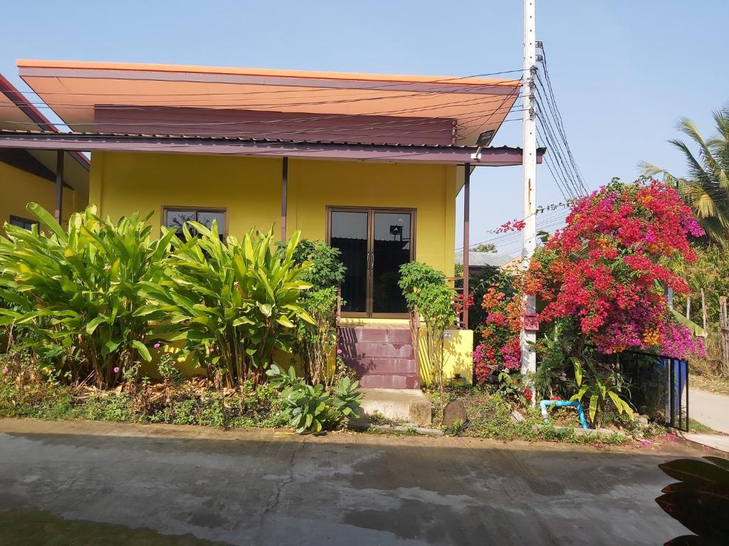 Prakhon ChaiLucky Home Prakhon Chai的一座黄色的小房子,种有植物和鲜花