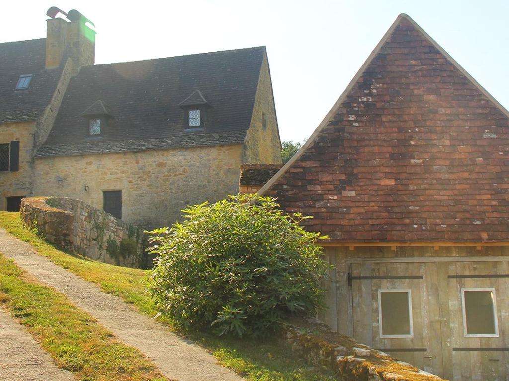 贝纳克和卡泽纳克Maison Linol的一座带棕色屋顶的古老石头建筑