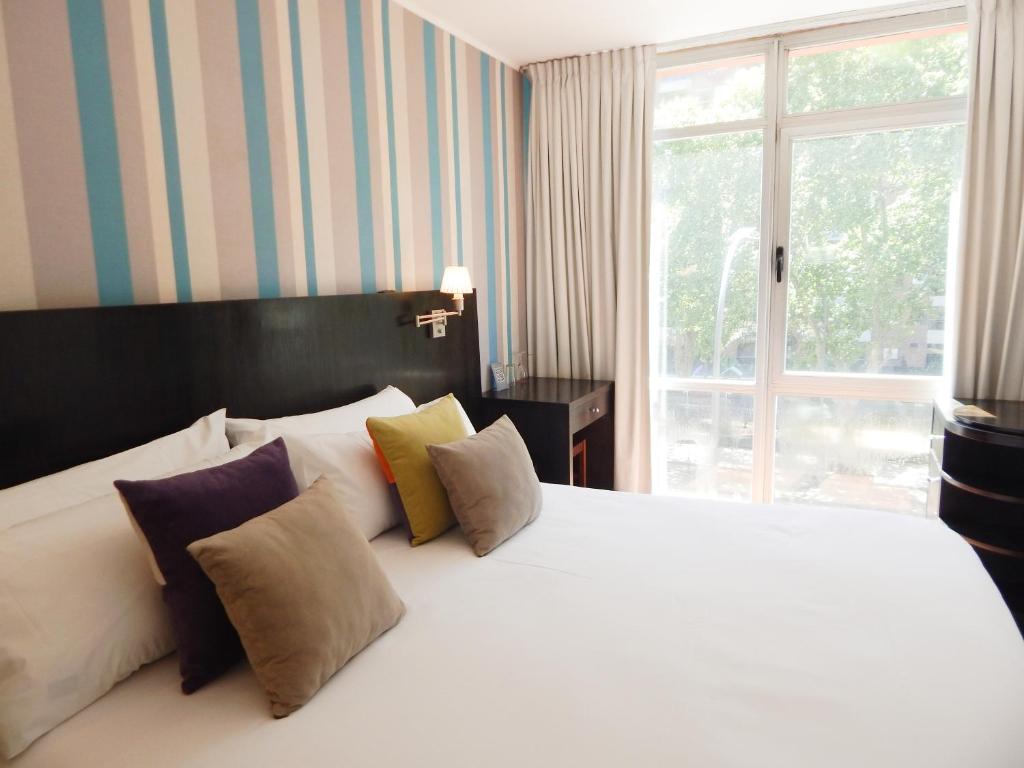 布宜诺斯艾利斯里贝拉苏尔酒店的卧室配有带枕头的白色床和窗户。