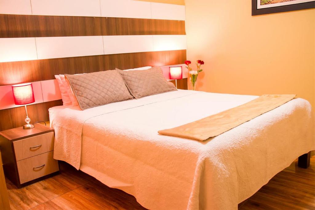 阿雷基帕Serk'ana Suite Hostal的一间卧室配有一张带两盏灯的大型白色床。