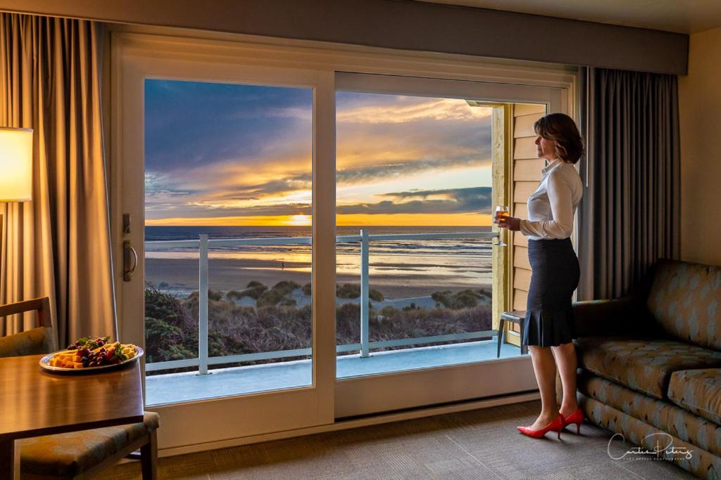 弗洛伦斯浮木海岸度假酒店的站在窗外望着大海的女人