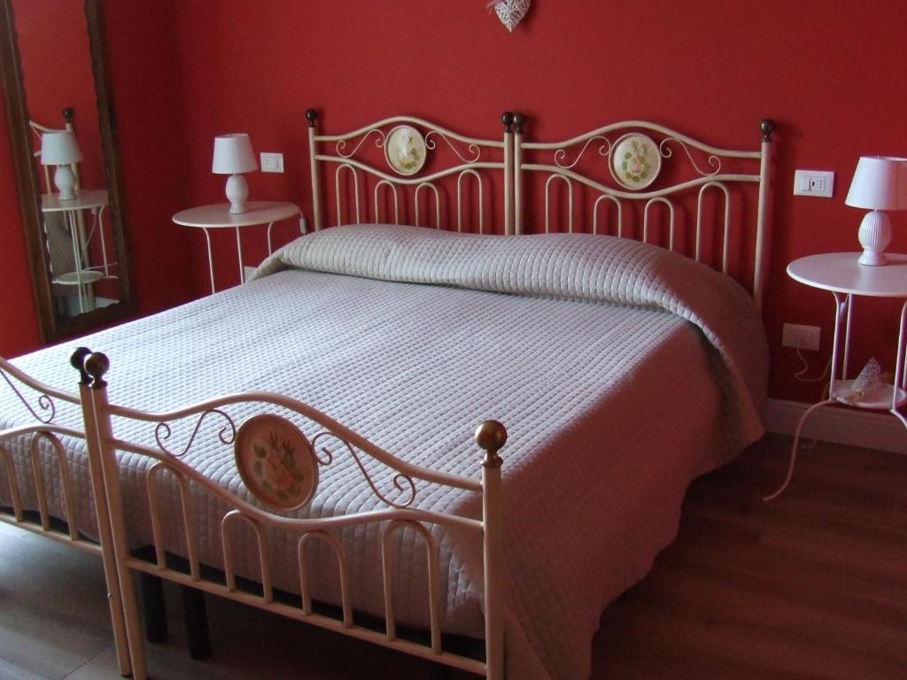 圣费利切德尔贝纳科B&B Solstizio d'estate的红色卧室内的一张床位,配有两张桌子