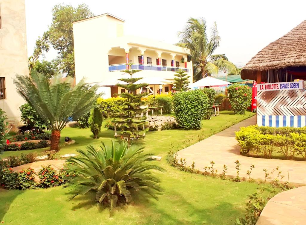 KpaliméHotel Ganiela的一个带棕榈树花园和大楼的度假村