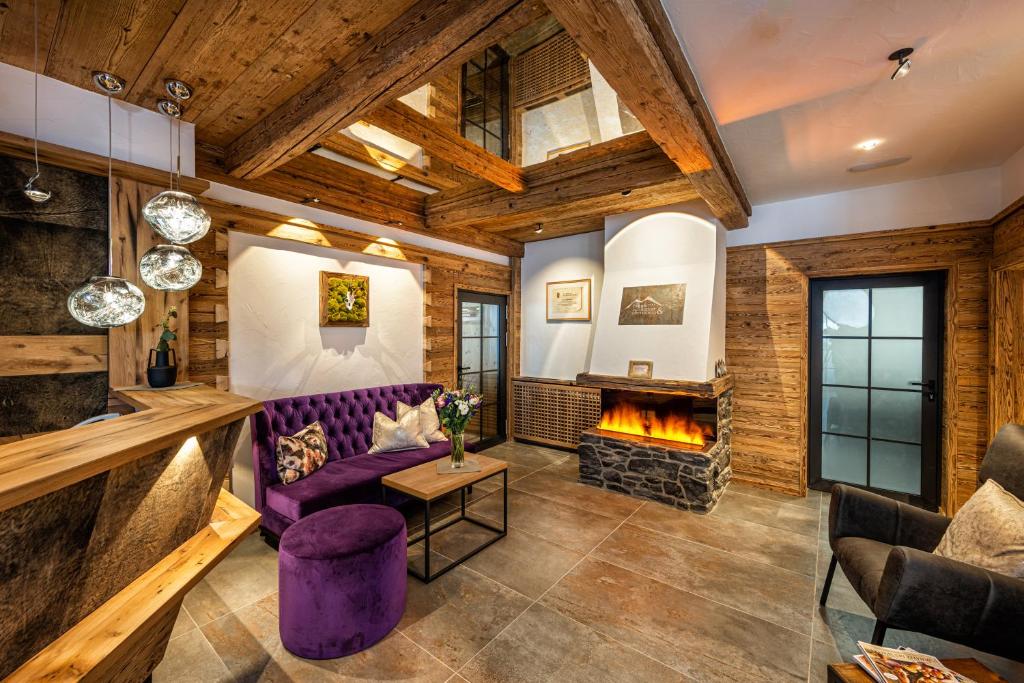 上陶恩Hotel Zehnerkar & Hotel Obertauern的客厅配有紫色沙发和壁炉