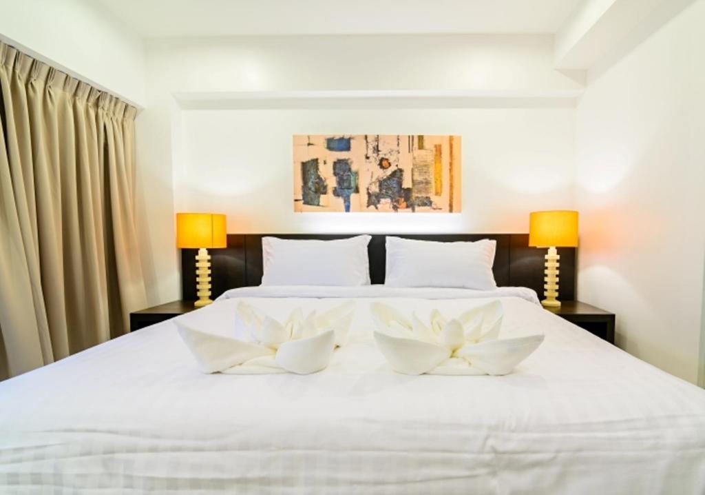 曼谷UMA公寓酒店的卧室配有白色的床,上面有两朵白色的花