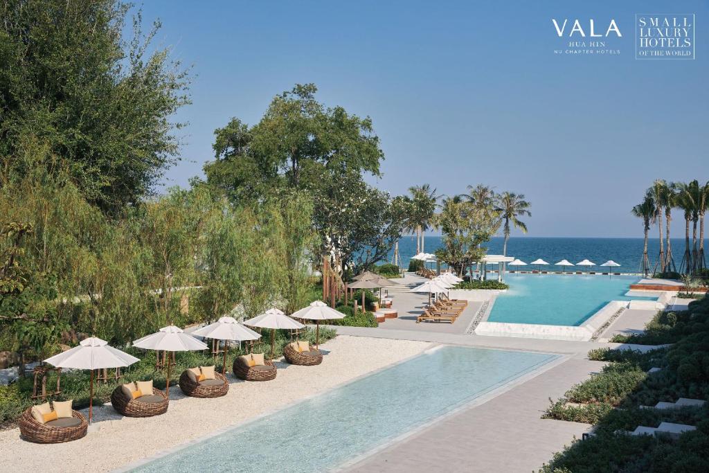 七岩VALA Hua Hin - Nu Chapter Hotels的一个带游泳池、椅子和遮阳伞的度假村