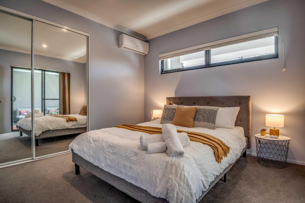 珀斯Maylands Boutique Apartments的一间卧室配有一张大床和镜子