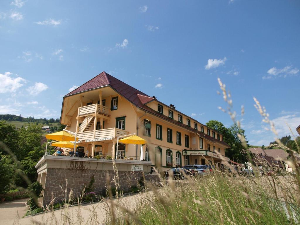 托特瑙Grüner Baum Naturparkhotel & Schwarzwald-Restaurant的黄色的建筑,前面有黄色的雨伞