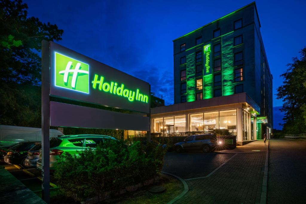伯恩茅斯Holiday Inn Bournemouth, an IHG Hotel的夜间在大楼前的酒店标志