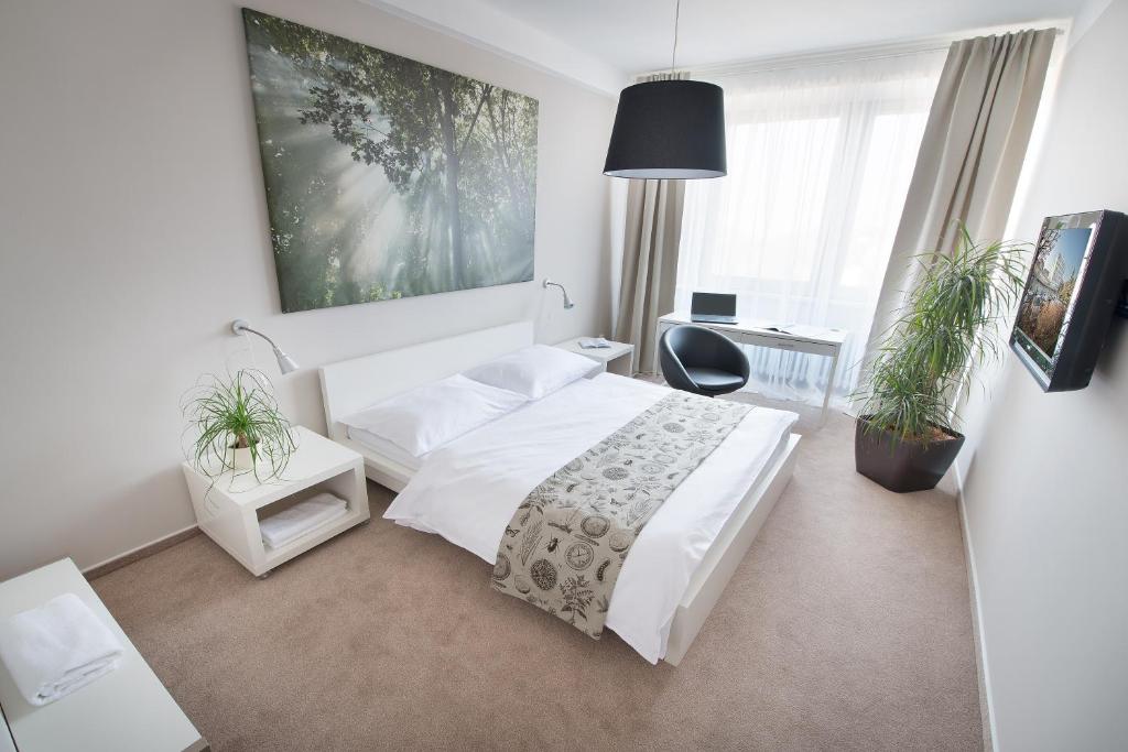 布拉格科特布斯酒店的一间酒店客房,配有一张白色的床和一张书桌