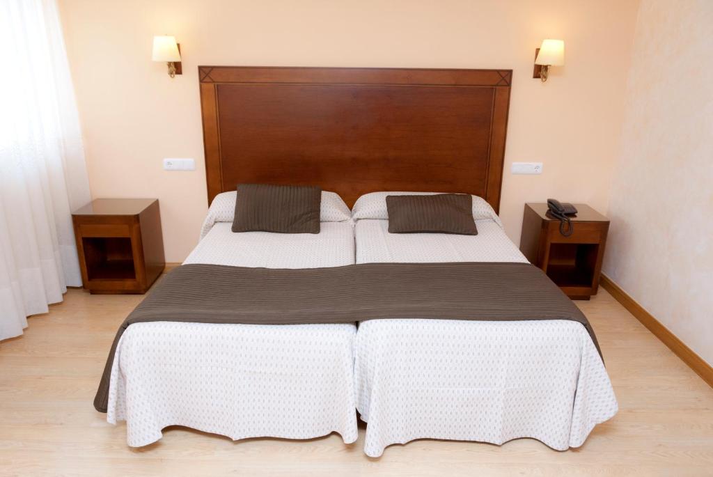 布尔戈斯布尔戈斯卡米诺圣地亚哥修道院酒店的一间卧室配有一张大床和两个枕头
