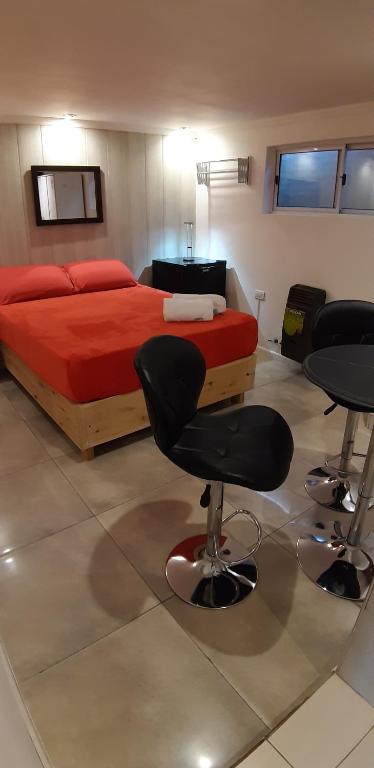 埃博森Departamentos Arrayanes的一间卧室配有一张床、两把椅子和一张桌子
