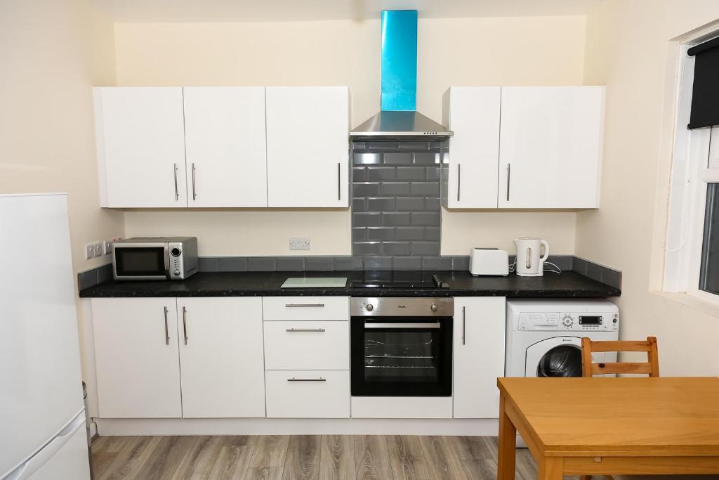 桑德兰AA Sunderland North的厨房配有白色橱柜和炉灶烤箱。