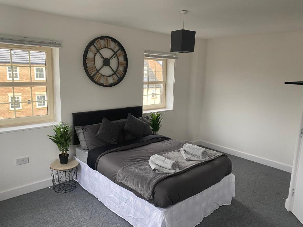 麦斯堡Doncaster Furnished House For Short Lets的卧室配有一张床,墙上挂着一个钟