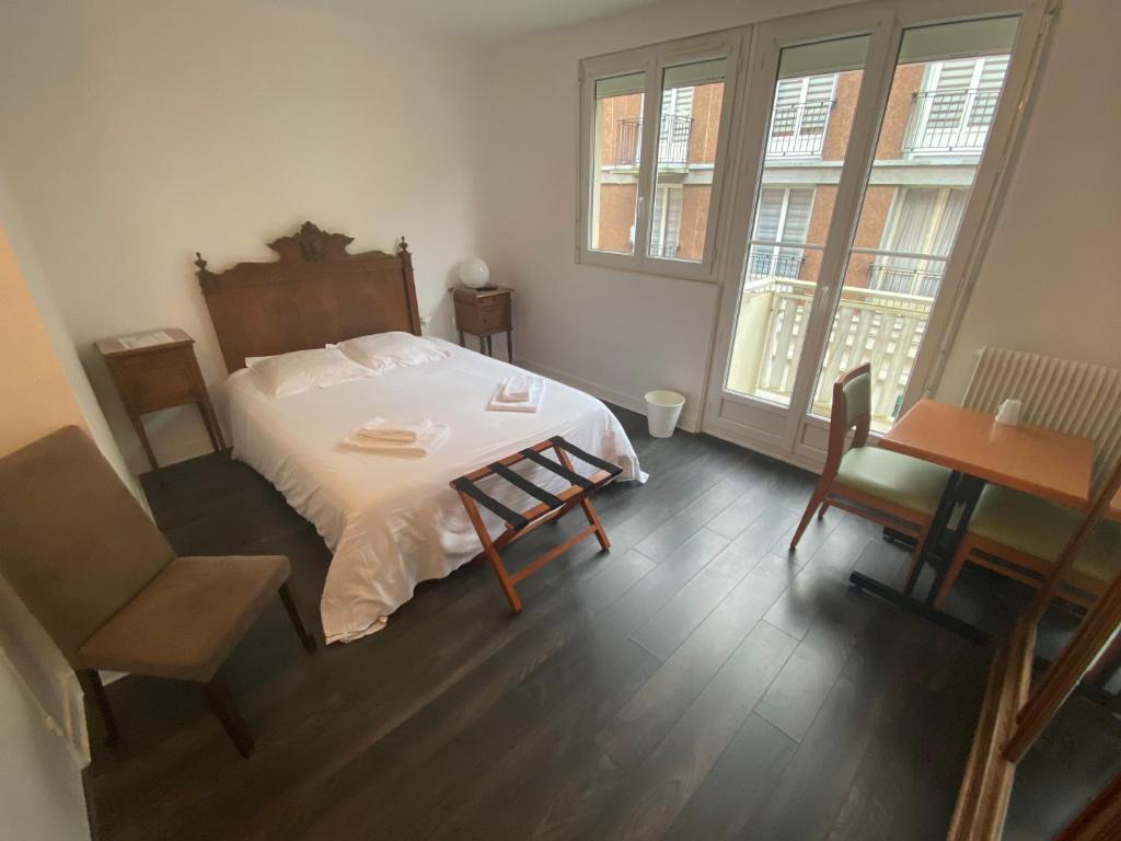 索姆河畔圣瓦莱里Hôtel les Remparts的卧室配有一张床和一张桌子及椅子