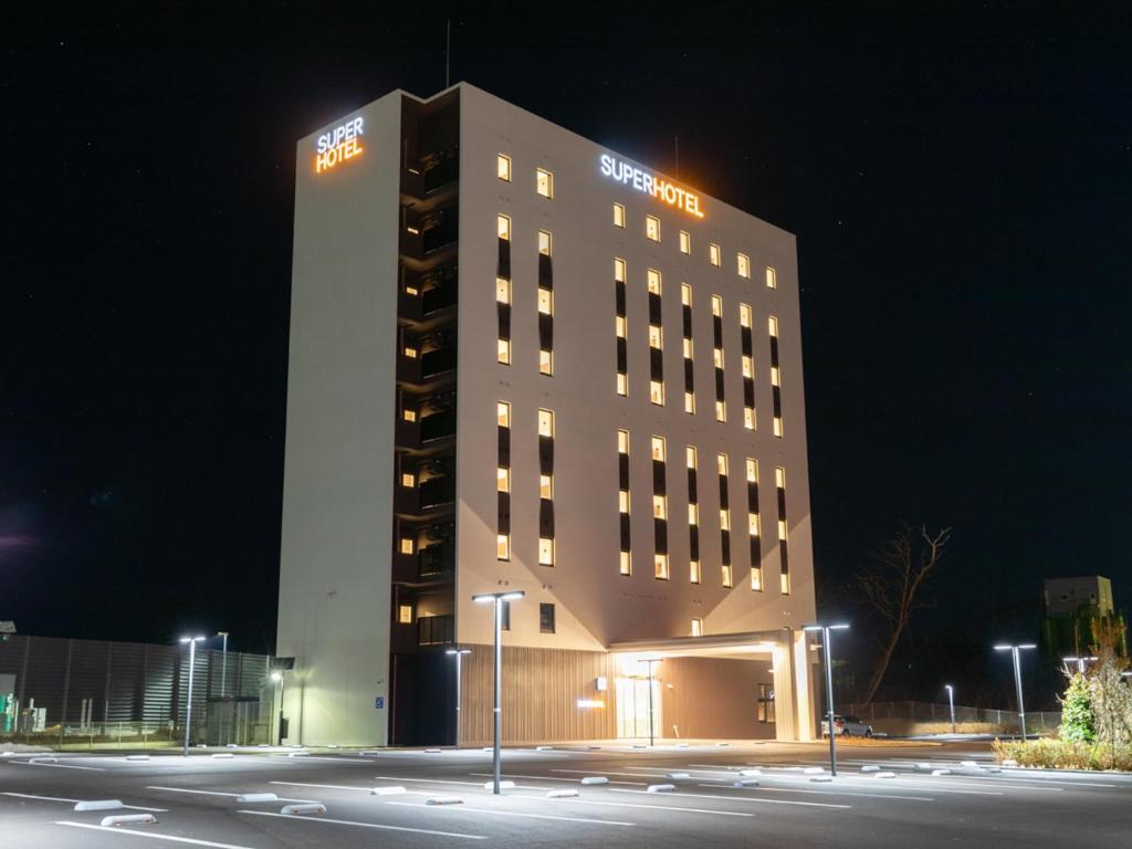 能美市Super Hotel Ishikawa Nomineagari Smart Inter的一座高大的建筑,晚上有标志