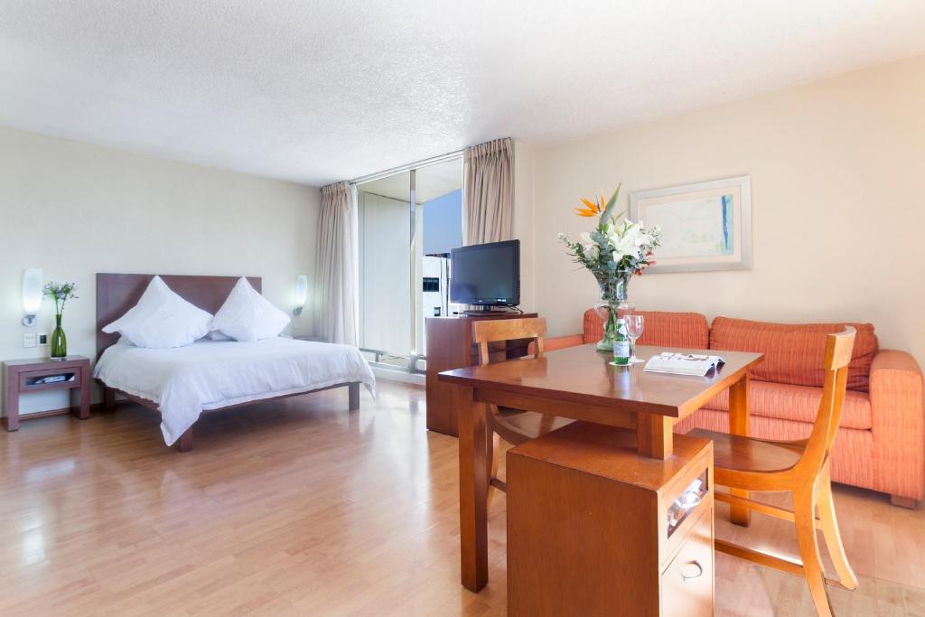 墨西哥城圣马力诺套房EXE酒店的酒店客房配有床、桌子和沙发。