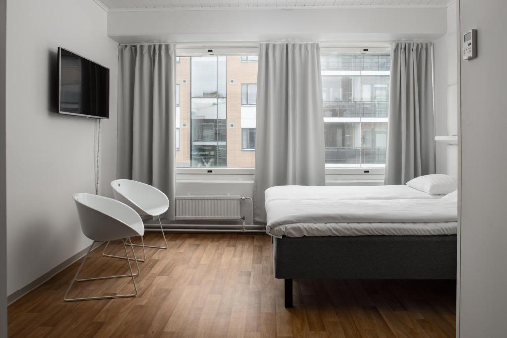 波里Omena Hotel Pori的一间卧室配有一张床、两把椅子和一个窗户