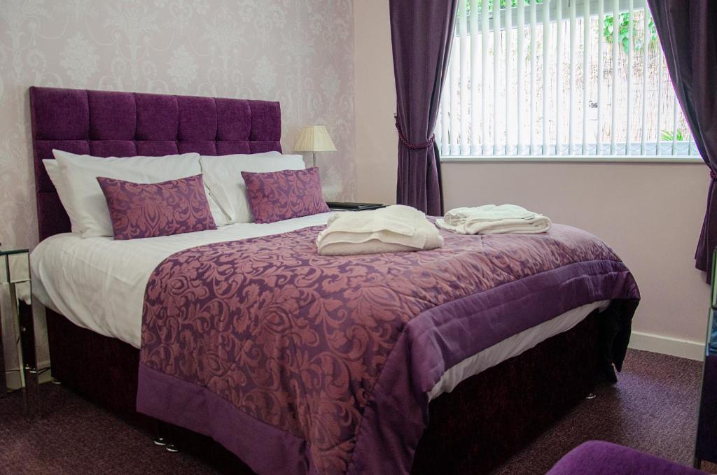 桑德兰The Lemonfield Hotel的一间卧室配有一张带紫色床单的大床和窗户。
