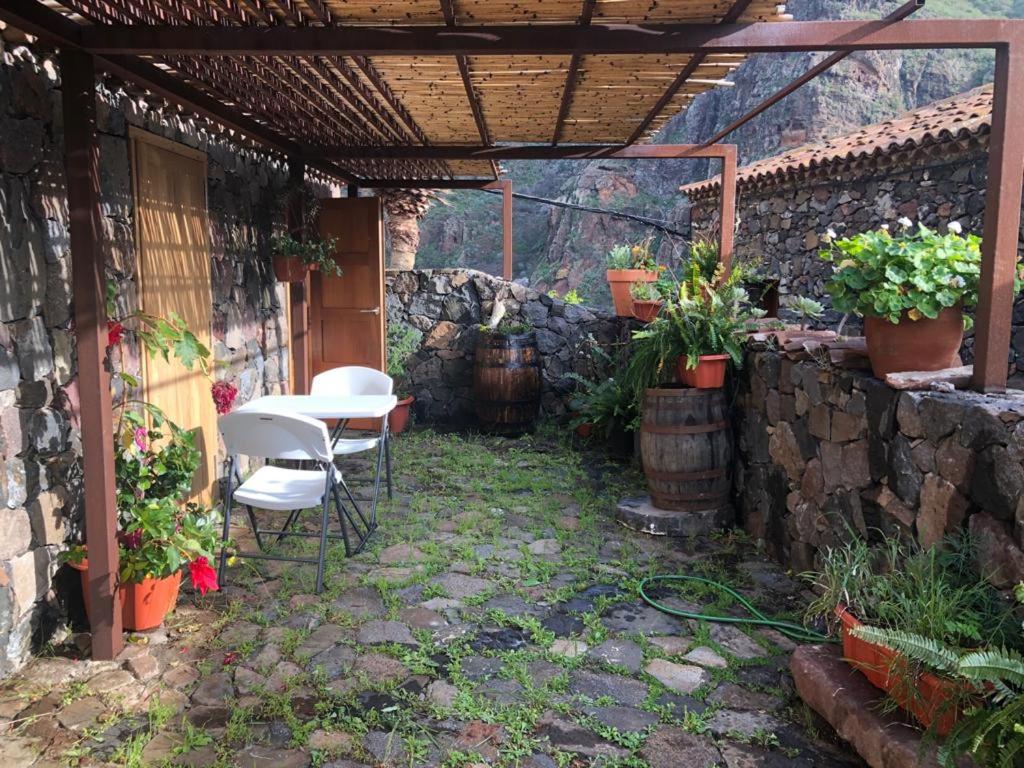 布埃纳维斯塔德尔诺尔特Casa Rural El Horno Masca的一个带桌椅和石墙的庭院
