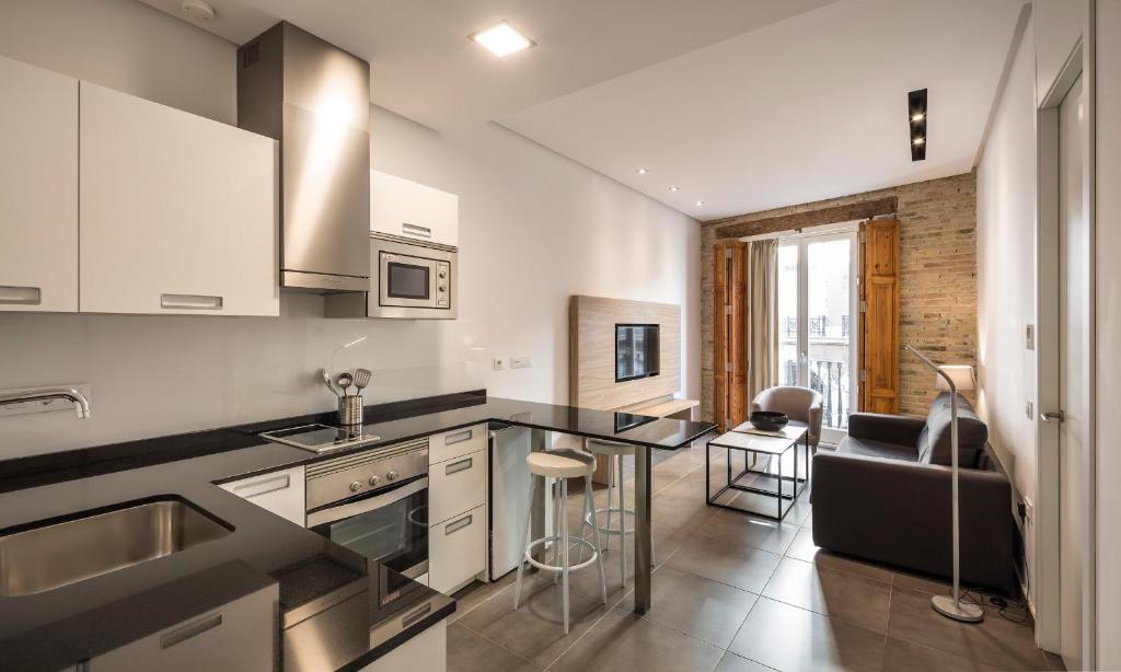 瓦伦西亚Mon Suites San Martin的一个带黑色台面的厨房和一间客厅
