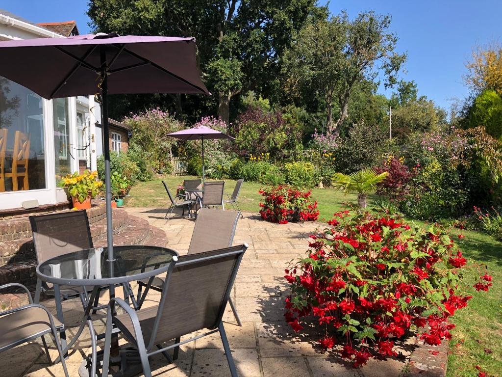 查尔伍德特朗博斯盖特威克住宿加早餐酒店的庭院配有桌椅和红色鲜花。