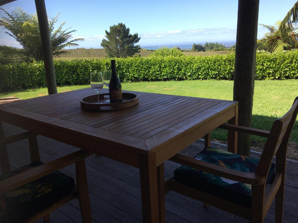 陶朗加Te Harinui - Peaceful rural escape的一张木桌、一瓶葡萄酒和两把椅子