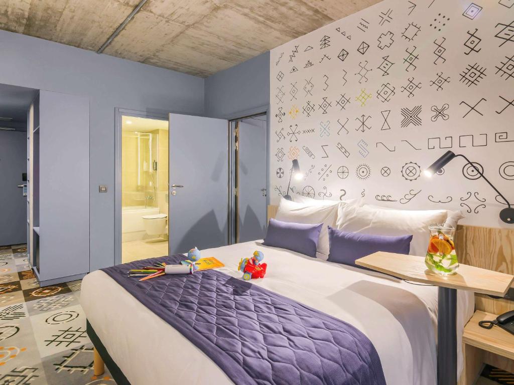 布加勒斯特ibis Styles Bucharest City Center的一间卧室配有一张带紫色棉被的床