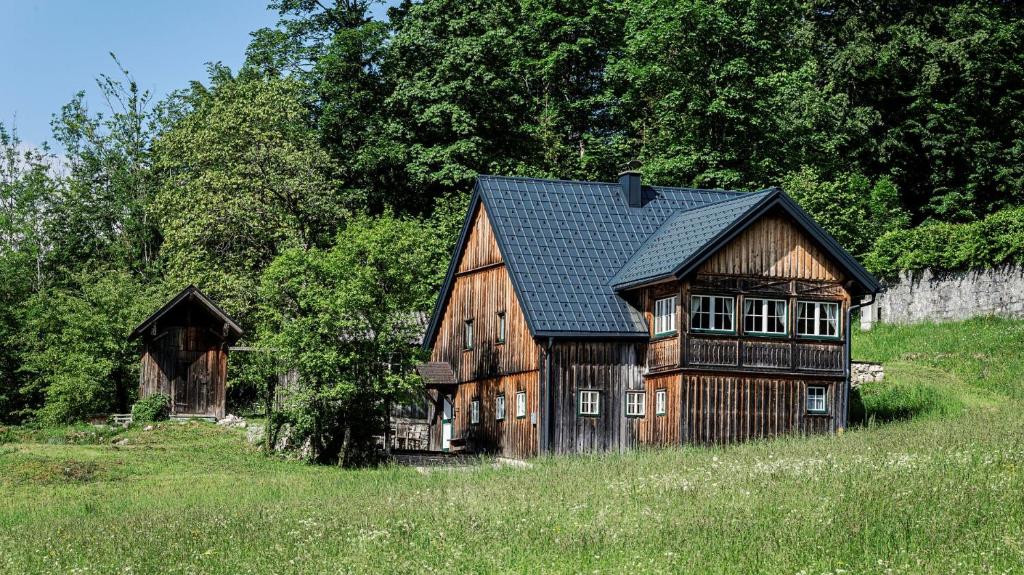 格伦德尔湖Das Haus am Grundlsee的田野上一座古老的木屋