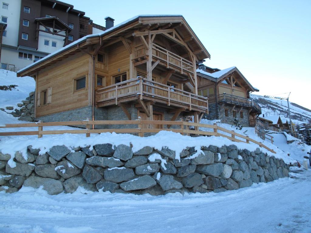 莱德萨阿尔卑斯CHALET L'ALPAGA 1的雪地中的小木屋,带有石墙