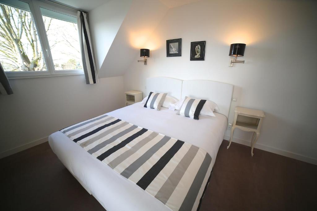 圣伊莱尔迪阿尔库厄勒里翁德奥尔酒店餐厅的卧室配有带条纹床单的白色床和窗户。