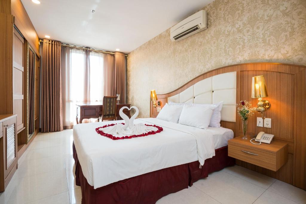 胡志明市Lam Kinh Hotel的一间卧室配有一张白色大床,上面有红花