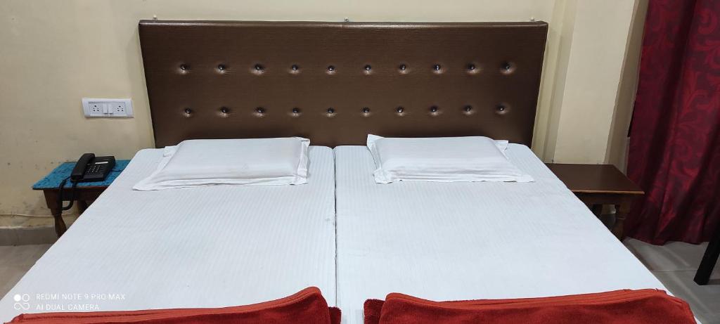 BalrāmpurHotel Avadh Balrampur的一张带两张白色床单和棕色床头板的床