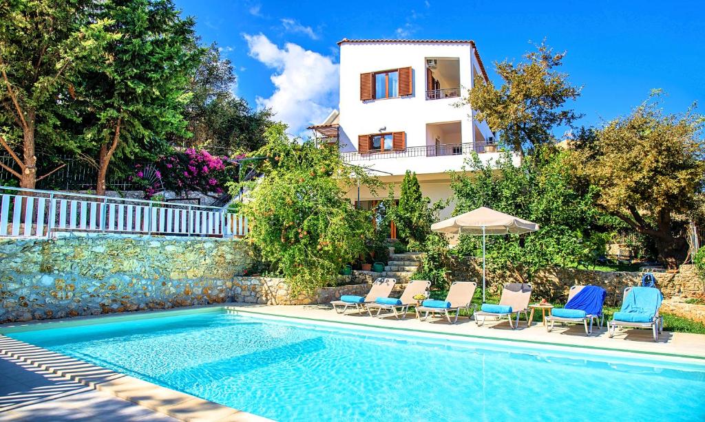 GeorgioupoliGrand View Villa Private Heated Pool的一座别墅,设有游泳池、椅子和一座房子