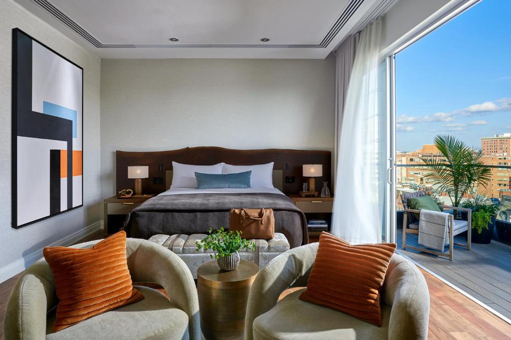 华盛顿杜邦环岛酒店的一间卧室配有一张床和两把椅子,并设有一个阳台