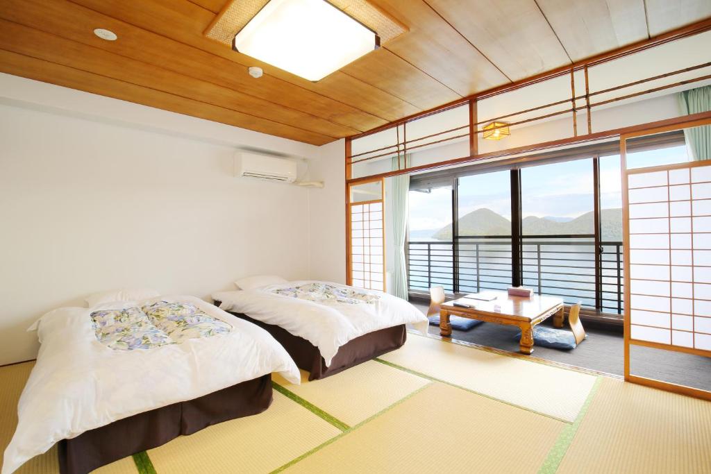 洞爷湖洞爷温泉华美传统日式旅馆的一间卧室设有两张床、一张桌子和窗户。