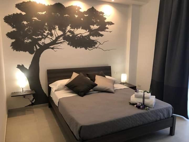 锡拉库扎Bealù的卧室配有一张床铺,墙上挂着一棵树