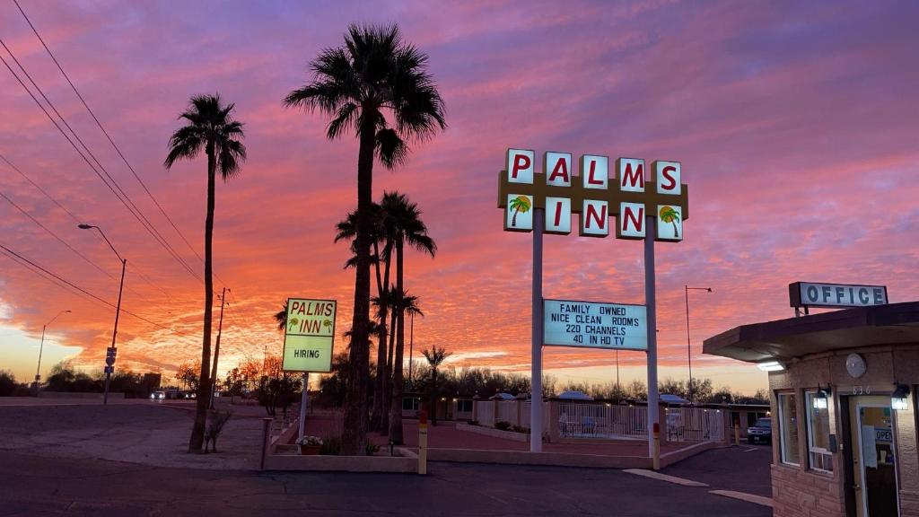 Gila BendPalms Inn的棕榈树和 ⁇ 虹灯标志的停车场
