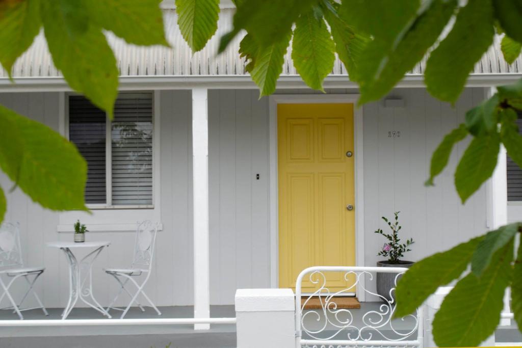 奥兰治Mary Lemon Cottage - Heritage Home的白色房子的黄色门,配有桌子和椅子