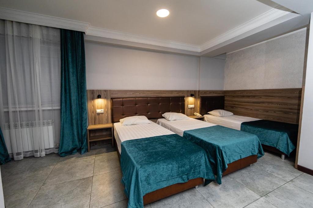 马哈奇卡拉Krepost Mini Hotel的酒店客房,配有两张带绿床单的床