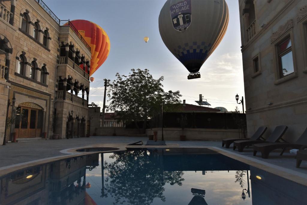 格雷梅Göreme Reva Hotel的两个热气球在游泳池上空飞行