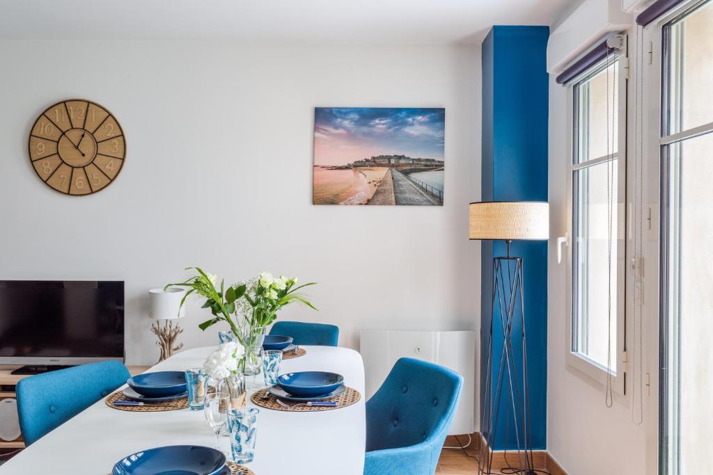 圣马洛L'Echo des Vagues的一间配备有白色桌子和蓝色椅子的用餐室