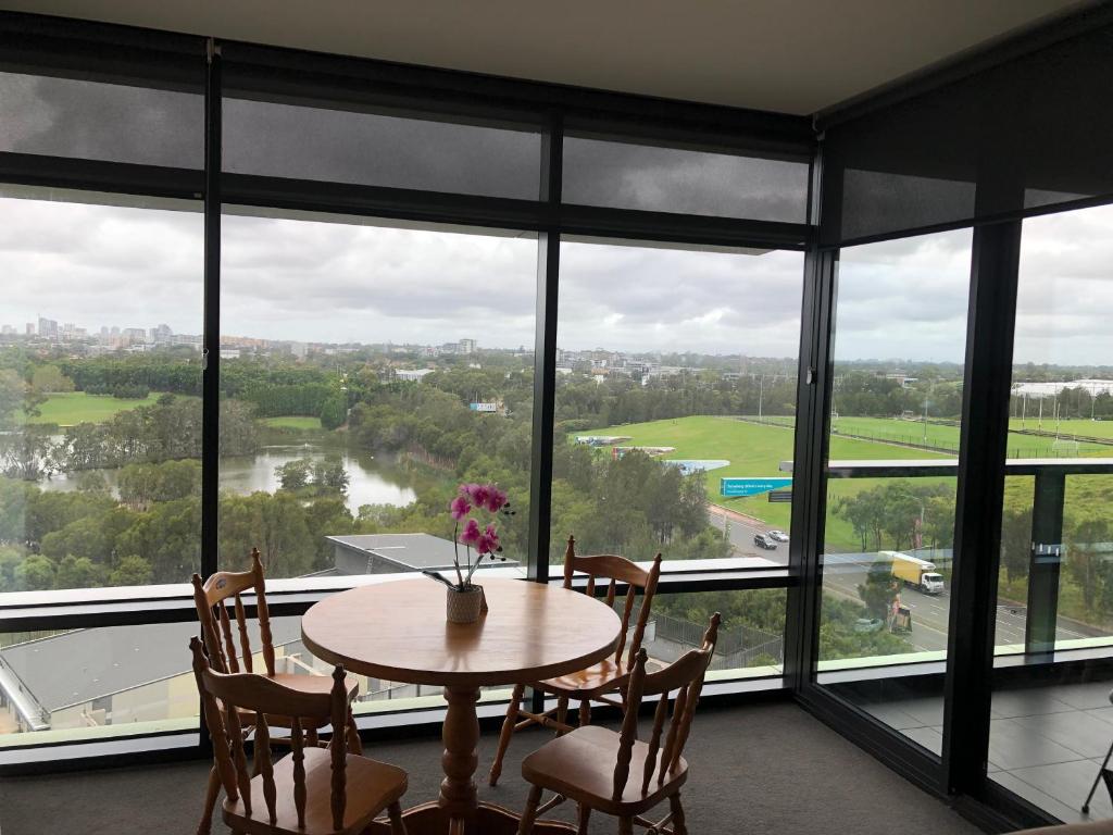 悉尼Parkview Modern Apartment w Parking @ Olympic Park的配有大窗户的客房内的桌椅
