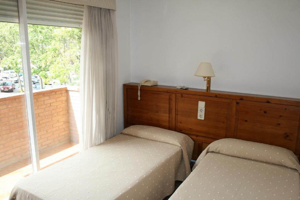 萨拉戈萨普恩特德彼德拉旅馆的一间卧室设有两张单人床和一个窗户。