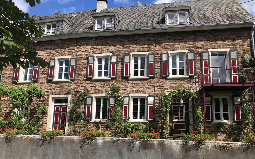 埃迪格尔-埃莱尔Das Moselhaus的一座带红色百叶窗和鲜花的老砖屋