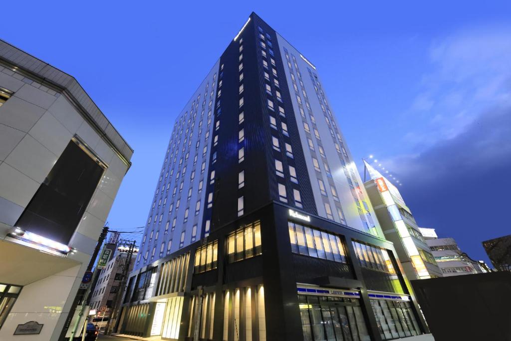 盛冈Richmond Hotel Morioka Ekimae的一座高大的黑色建筑,窗户在城市里